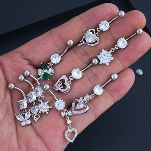 Detailed close-up of silver belly button rings with butterfly, clover and heart pendants