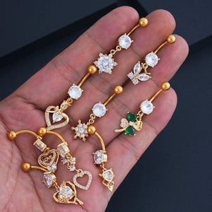 Close-up of gold navel rings set with butterfly and heart zircon pendants