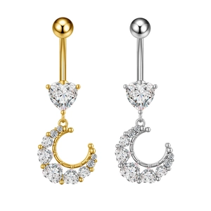 Detail van goud en zilver hartvormige navelpiercings met ster en maan zirkoon hangers