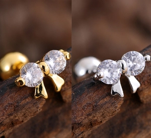 Detail of bow-shaped stud earrings featuring clear round cubic zirconia in gold and silver