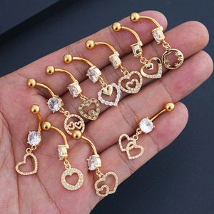 Detailed view of nine gold heart belly rings with zircon inlays held in hand