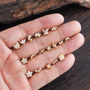 Miniature gold plated cartilage studs with micro-paved zircons held in a palm