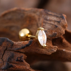 Macro view of gold-plated marquise zircon stud earring on a rustic wooden surface