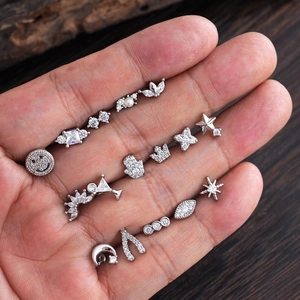 Set de pendientes minimalistas de acero inoxidable plateado con circonitas en la mano