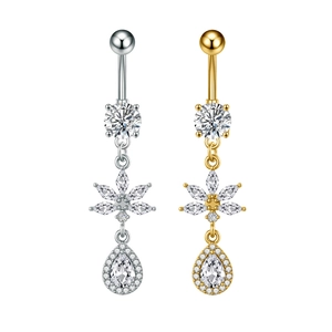 Dettaglio di piercing all'ombelico argento e oro con motivo floreale e zircone a goccia