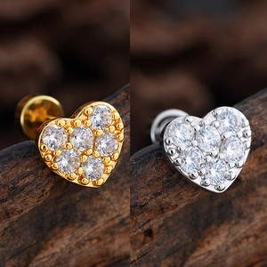 Macro detail of heart-shaped labret studs with micro-paved zircons in gold and silver