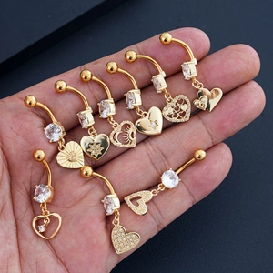 Detalle de un set de 8 piercings para ombligo dorados con colgantes de corazón, luna y circón