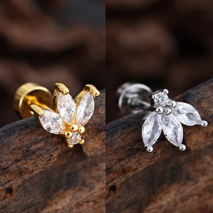 Macro shot of gold and silver leaf piercing studs with marquise zircons on wood