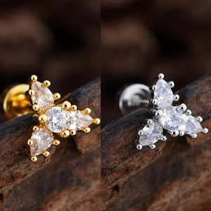 Primer plano detallado de pendientes de flor en oro y plata con circonitas brillantes