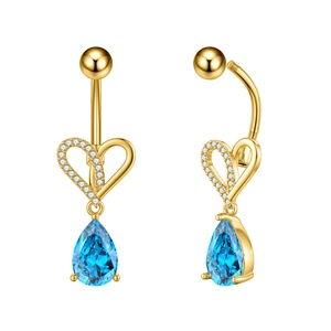 Macro detail van gouden hart navelpiercing met blauwe zirkoon en sprankelende witte steen