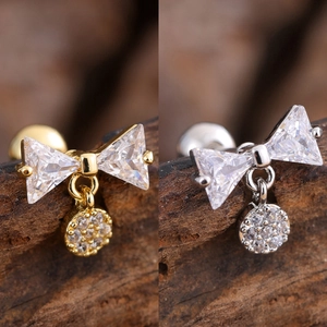 Detailed macro view of bow-shaped stainless steel earrings with cubic zirconia in gold and silver