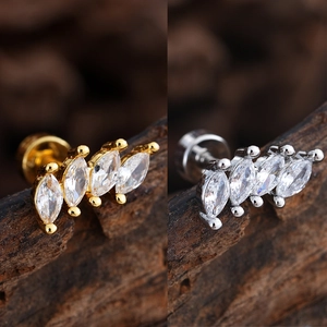 Detalle de pendientes de circonita con corte marquesa en oro y plata sobre madera rústica