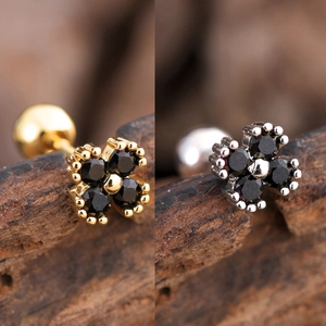 Detailed macro view of gold and silver flower stud earrings with black zircon stones