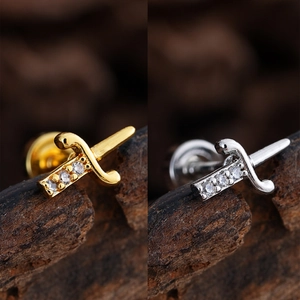 Macro shot of sword-shaped stud earrings with zircons and gold plating details