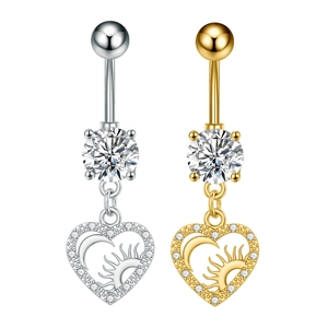 Detalle de piercings de ombligo en forma de corazón con colgantes de luna y sol de circón