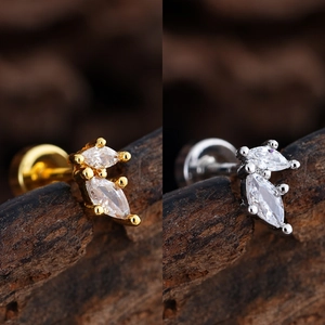 Macro view of gold and silver marquise-cut zircon stud earrings on a dark wood background