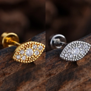 Primer plano de pendientes de ojo dorados y plateados con circonitas micro-incrustadas