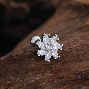 Macro detail of silver flower labret stud with marquise-cut zircon petals on dark wood