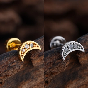 Macro detail of crescent moon helix studs with micro-set cubic zirconia in gold and silver