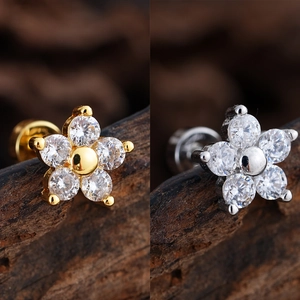 Detailed macro view of gold and silver flower stud earrings with sparkling cubic zirconia