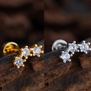 Macro shot of micro-pave three-stone curved stud earrings in gold and silver finish
