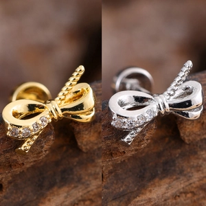 Close-up of gold and silver bow stud earrings with sparkling cubic zirconia on wood background
