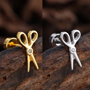 Detalle de los pendientes con forma de tijeras en oro y plata con circonita brillante