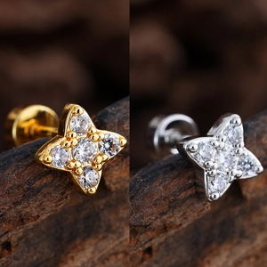 Primer plano de pendientes de estrella en oro y plata con circonitas y cierre de rosca