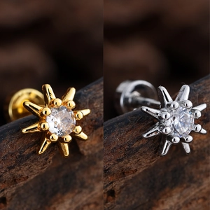 Macro detail of star-shaped stud earrings in gold and silver with cubic zirconia stones
