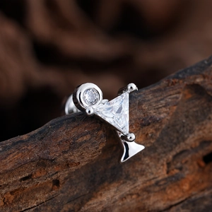 Detalle macro de pendientes geométricos de plata con circonitas sobre fondo de madera natural