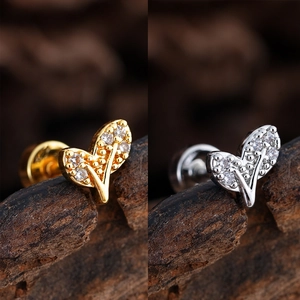 Vista detallada de aretes de corazón con circón en oro y plata sobre fondo de madera
