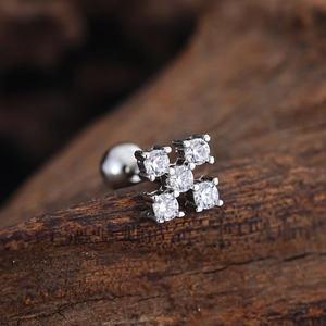 Macro shot of stainless steel stud earring with five cubic zirconia stones on wood