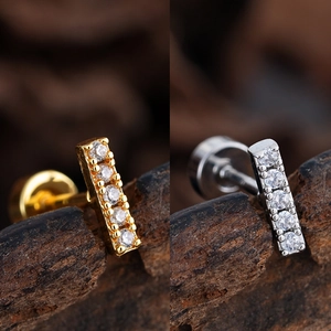Detailed macro view of gold and silver vertical bar earrings with five inlaid zircons