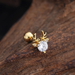 Macro detail of gold reindeer cartilage stud with cubic zirconia on wood background