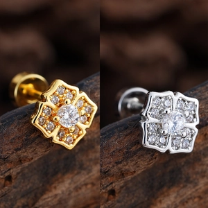 Detail of flower zircon stud earrings with gold and silver finish on wood background