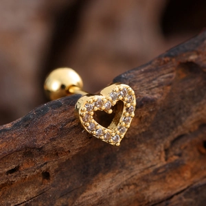 Macro detail of a heart-shaped gold earring with cubic zirconia on a rustic wood surface