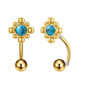 Dettaglio macro del piercing ombelico fiore dorato con pietra turchese blu e barra curva