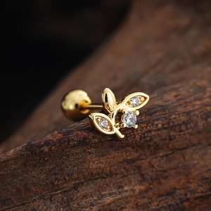 Macro shot of gold flower cartilage stud with cubic zirconia and screw ball back on wood