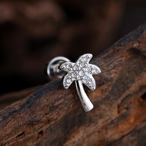 Pendiente de plata con forma de cocotero y circonitas sobre fondo de madera noble