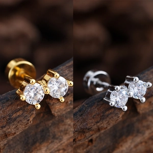 Detalle de pendientes de doble circonita en oro y plata con rosca sobre fondo de madera