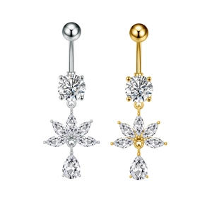 Detalle de piercings de ombligo en plata y oro con diseño de loto y circonitas de gota