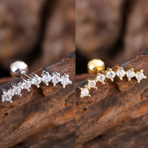 Detail view of silver and gold zircon curved ear studs with secure ball screw backs