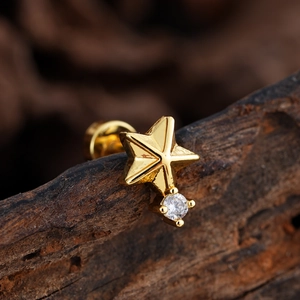 Detalle macro de pendiente de estrella dorada con circón sobre superficie de madera