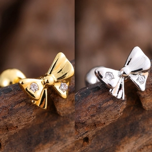 Detail view of bow-shaped stud earrings in gold and silver finish with small zircons