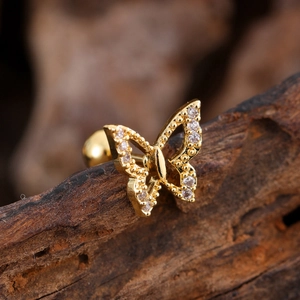 Macro detail of a golden butterfly ear stud featuring cubic zirconia micro-inlay accents