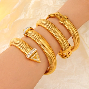 Macro shot of gold snake-shaped ribbed bracelet with shimmering pavé set rhinestones