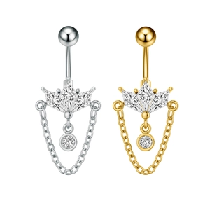 Detalle macro de piercings de ombligo en forma de corona con circonitas y cadenas colgantes