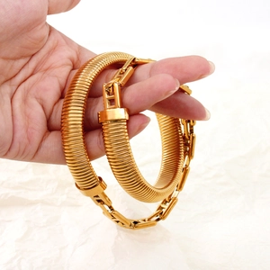 Detailed macro view of wide golden snake bone chain bracelet with polished finish and fold-over clasp