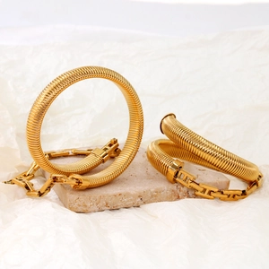 Three flexible gold titanium steel spring bracelets with H-link clasps on stone display