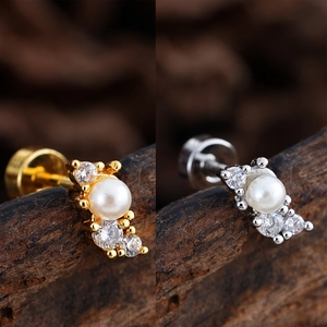 Vista macro de piercings con perlas y circonitas en acabados dorado y plateado fino